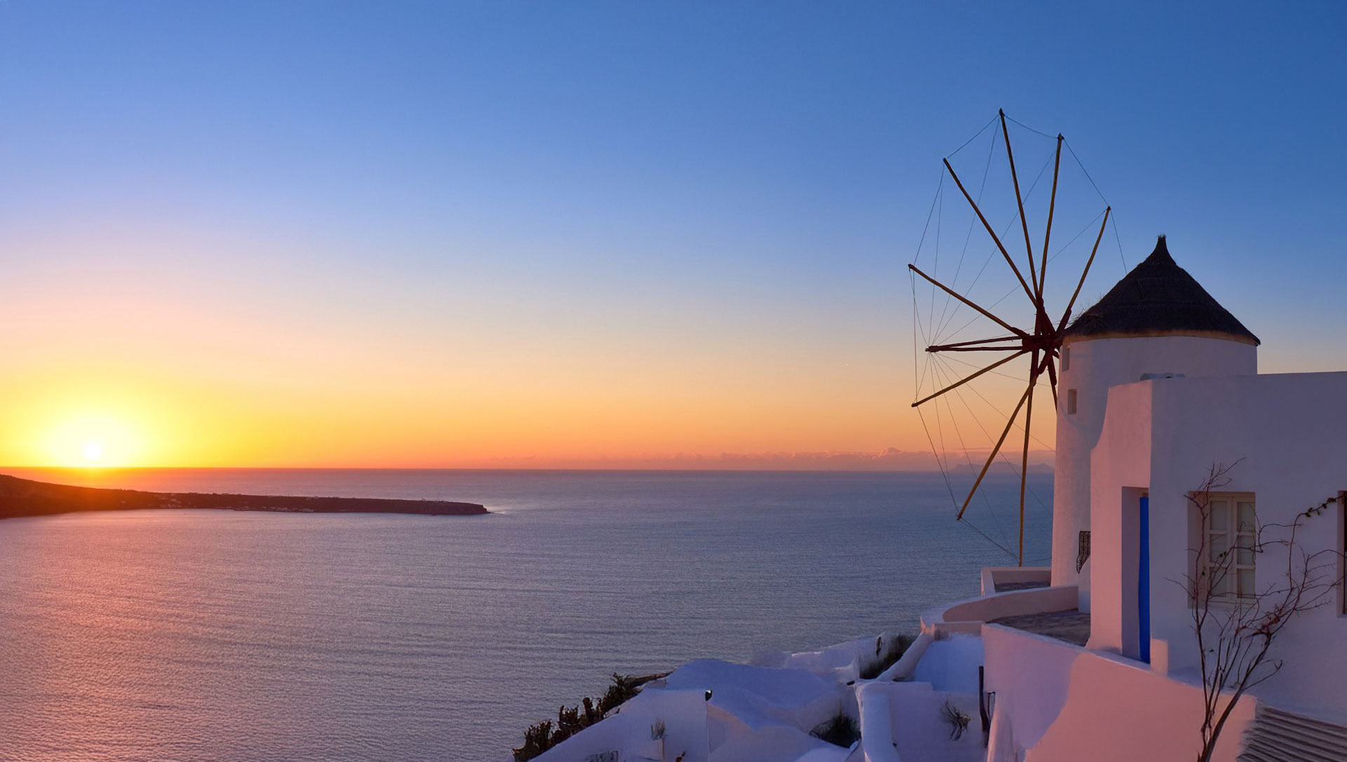 Traditional windmill overlooking the caldera at sunset in Santorini, Cyclades Islands, Greece