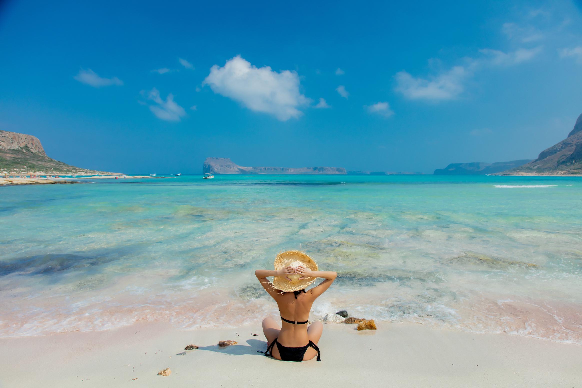Woman relaxing on Balos Lagoon beach with turquoise water in Crete, Greece