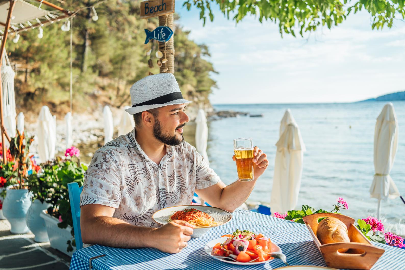 Man enjoying Greek food and beer at a seaside taverna in Greece