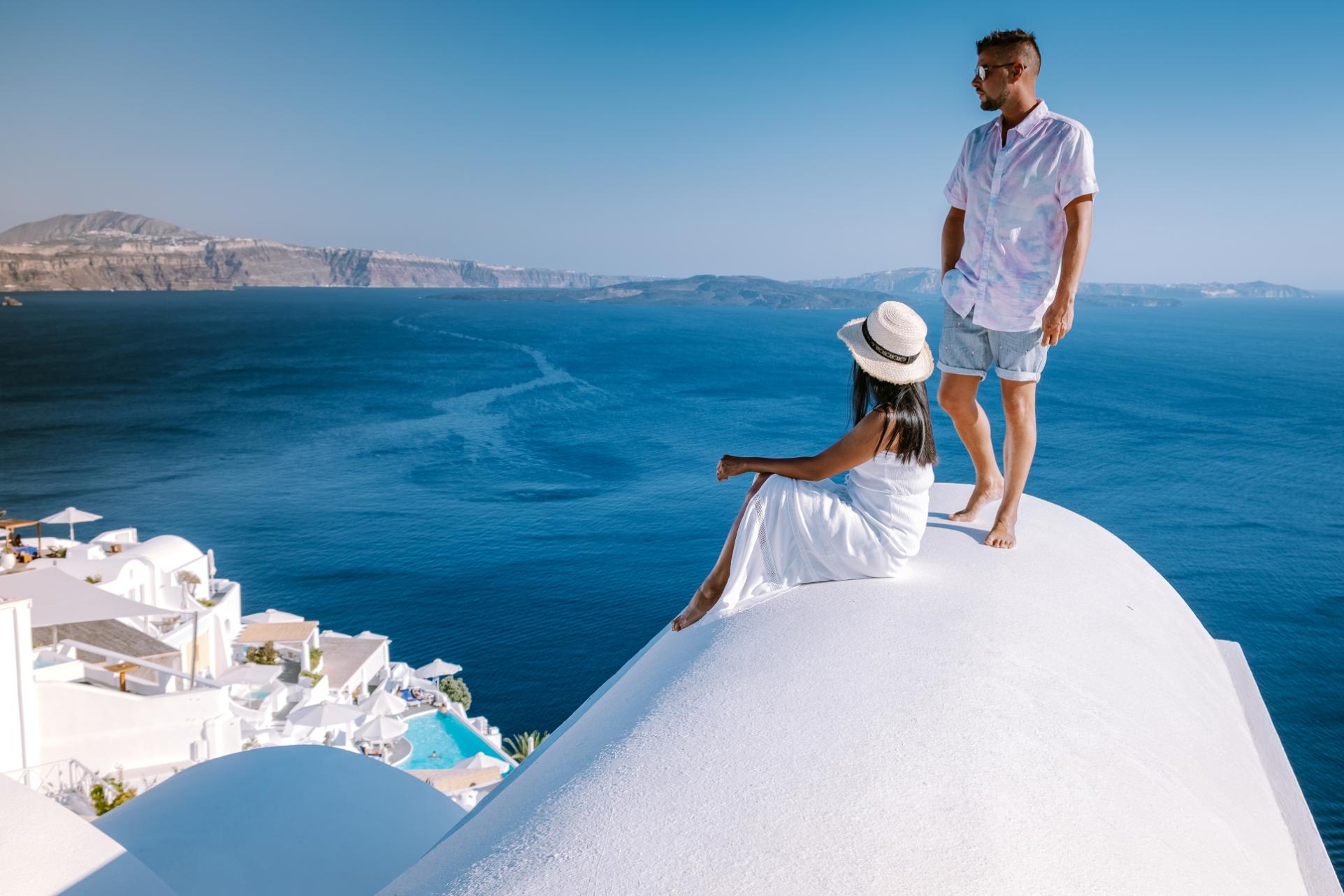 Couple enjoying panoramic caldera view from Oia village in Santorini, Cyclades Islands, Greece