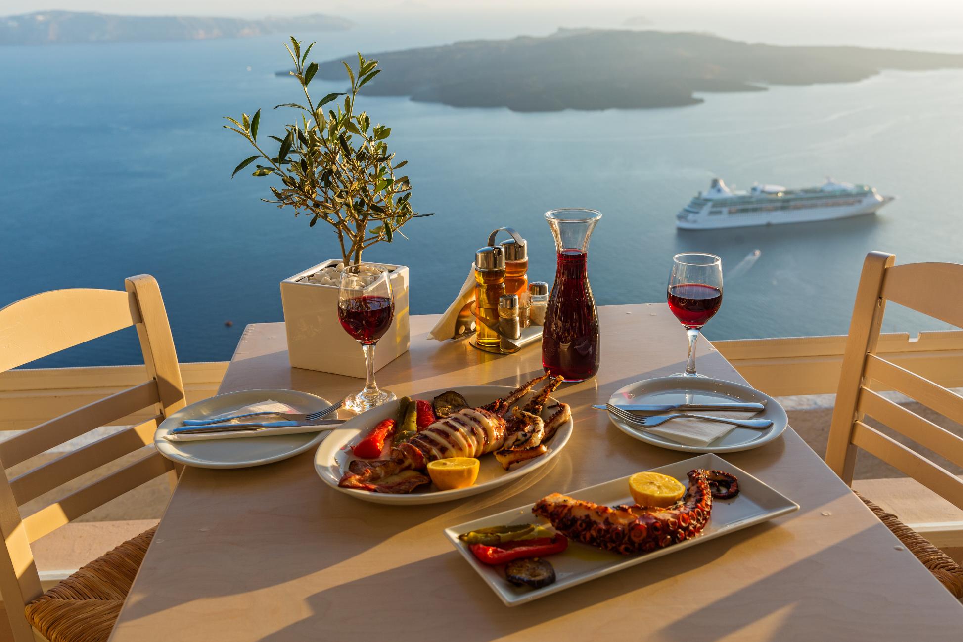 Seafood dinner with wine overlooking the Santorini caldera and Aegean Sea in Greece
